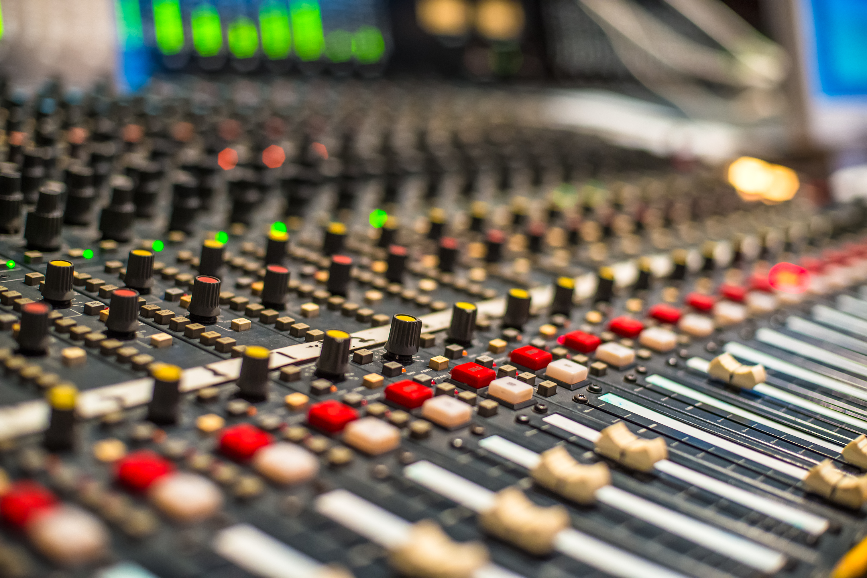 Close-up of a large studio mixing console with rows of knobs and faders